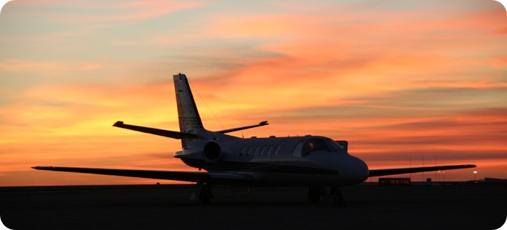 A plane is sitting on the runway at sunset.