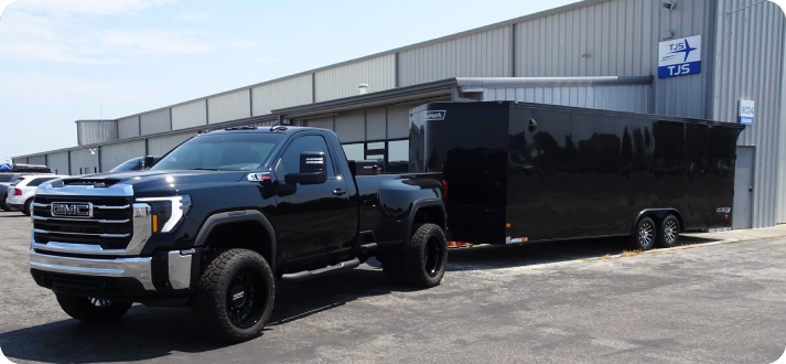 A black truck pulling a trailer in the parking lot.